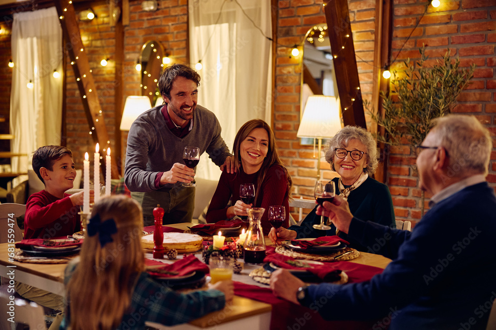 Happy man raising toast during family dinner at dining table on Christmas Eve.