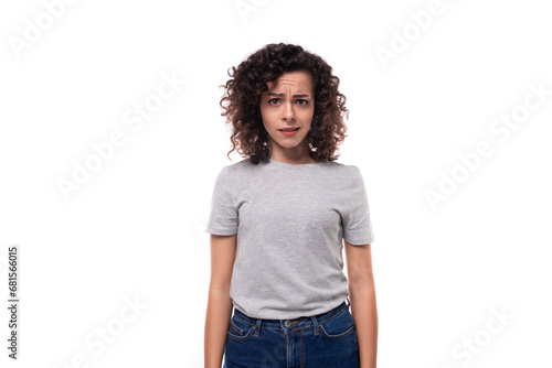 upset slender curly brunette promoter woman with glasses is dressed in a gray basic t-shirt on a white background with copy space