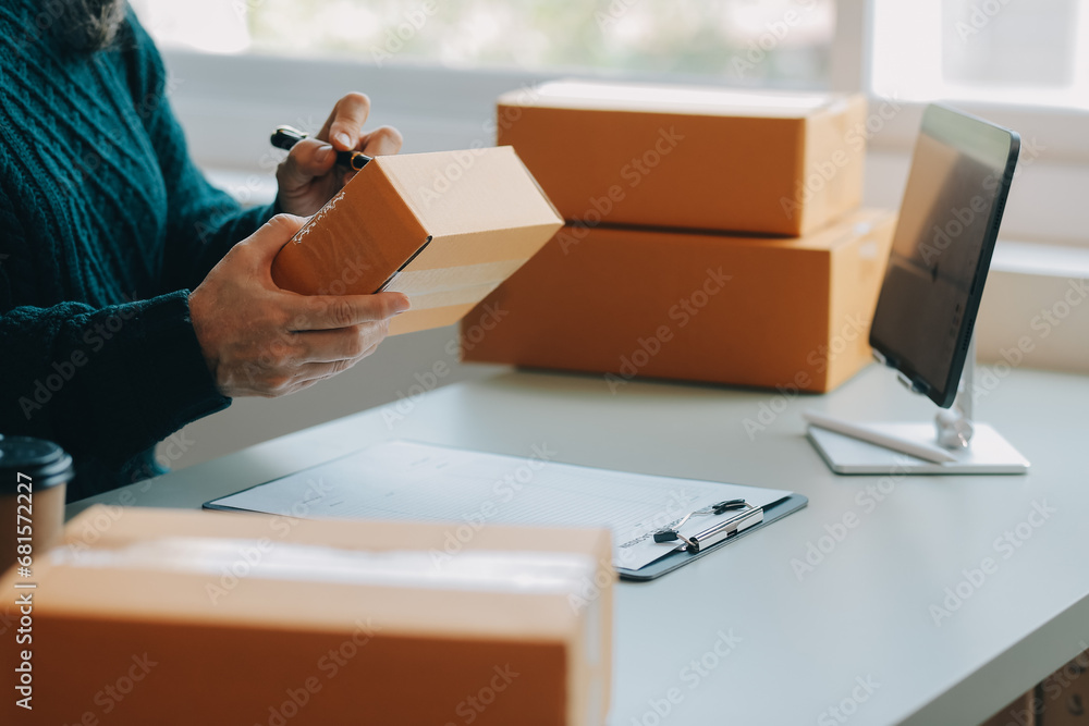 Startup SME small business entrepreneur of freelance Asian woman wearing apron using laptop and box to receive and review orders online to prepare to pack sell to customers, online sme business ideas. - obrazy, fototapety, plakaty 