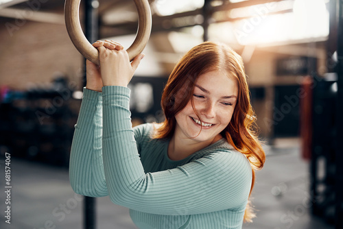 Laughing young woman holding onto rings during a gym workout photo