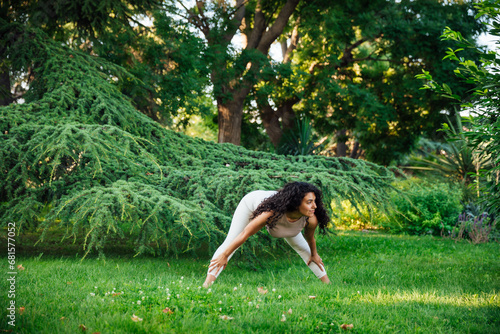 Young brunette asian woman practicing yoga during workout in park