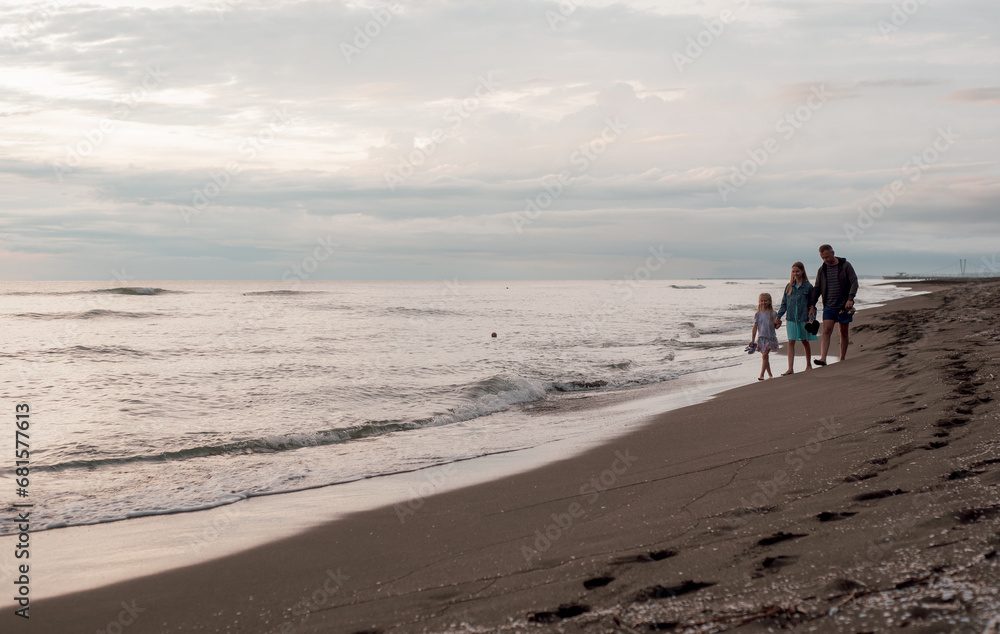 A family walks along the sandy beach. Sea coast.