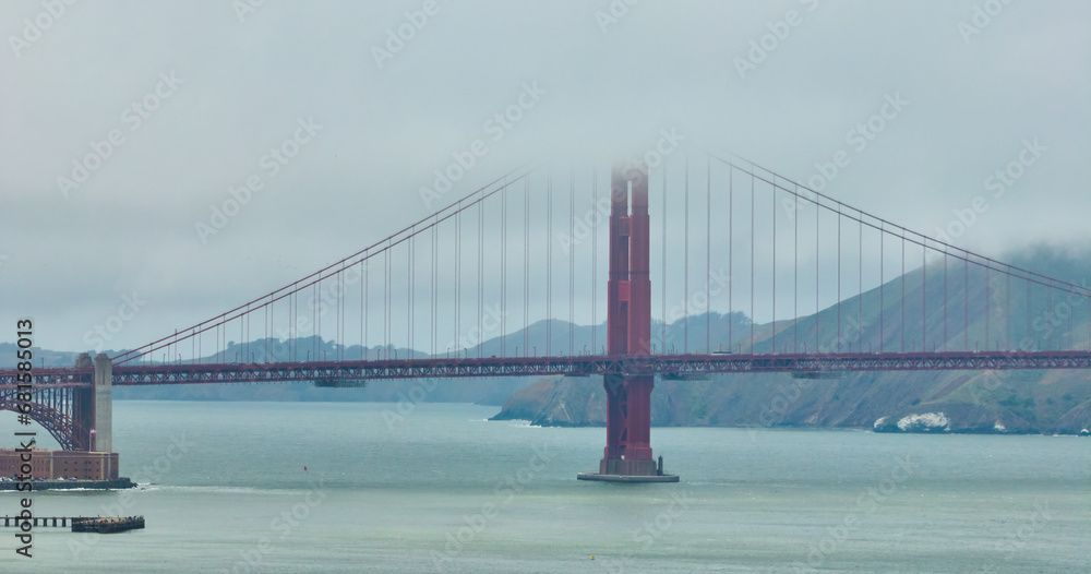 Fototapeta premium Golden Gate Bridge shrouded in cloudy mist on foggy day aerial over San Francisco Bay, CA