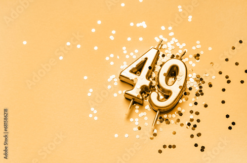 49 years birthday celebration festive background made with golden candle in the form of number Forty nine lying on sparkles. photo