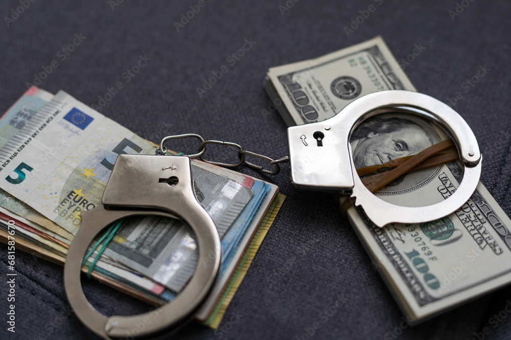 Police handcuffs lie on many dollar bills isolated on black background. Crime. justice and money. Concept of crime and corruption with handcuffs. Police handcuffs lie on many dollar bills isolated on black background. Crime. justice and money. Concept of crime and corruption with handcuffs.
