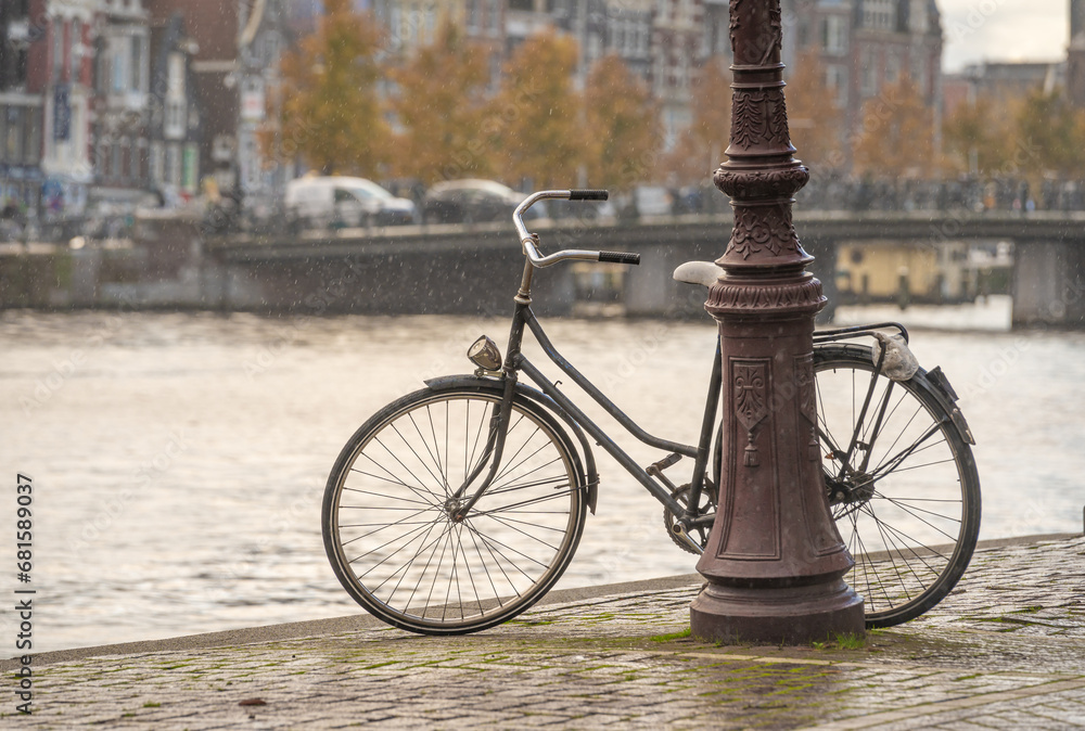 Old dutch bike by the canal in Amsterdam on a rainy autumn day