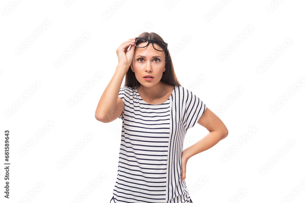 young european brunette woman in a striped sweater wears glasses for vision correction on a white background with copy space young european brunette woman in a striped sweater wears glasses for vision correction on a white background with copy space
