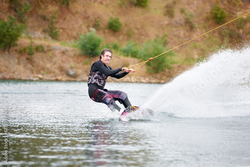 Spray, wakeboarding and adventure, man on lake with outdoor fun, fitness and wave splash. Balance, water sports and person on river with freedom, speed and energy for surfing challenge, ski and trick © Cameron M/peopleimages.com