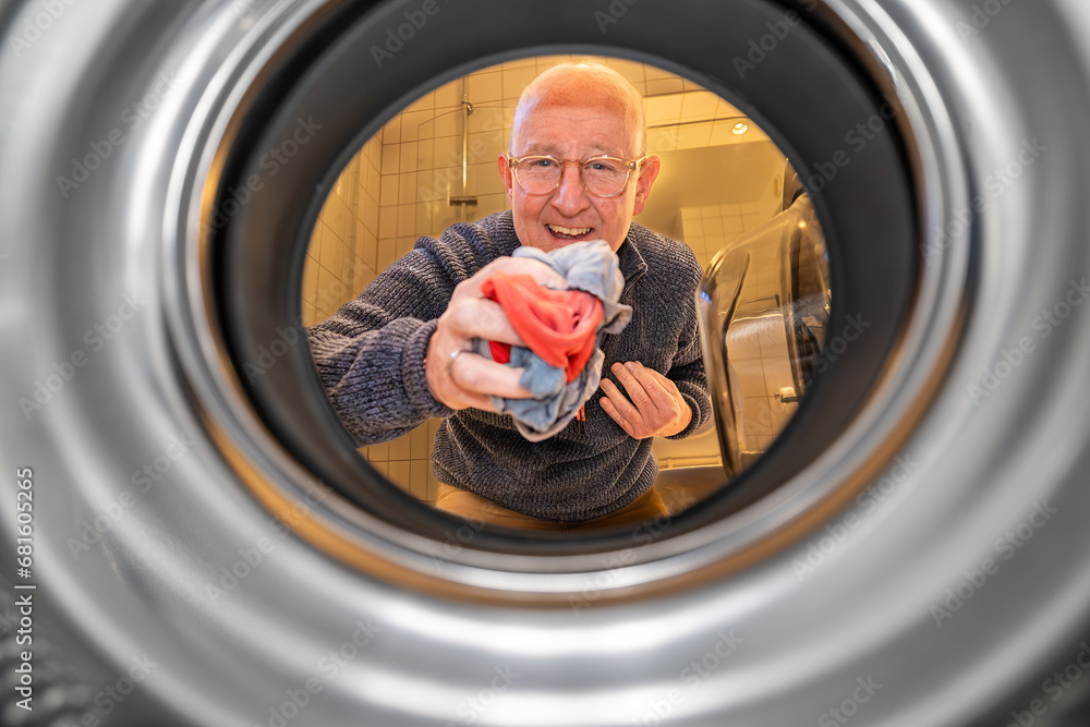 A man fills a washing machine with laundry. A man fills a washing machine with laundry.