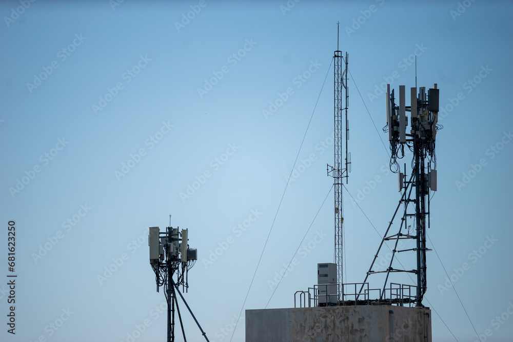 Telecommunication tower with blue sky and white clouds, technology background.