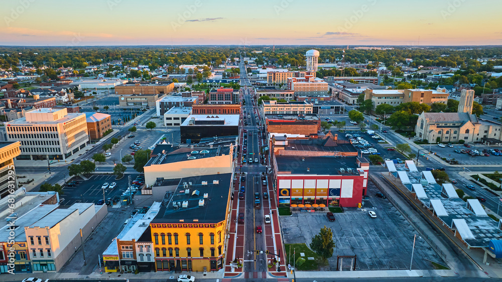 S Walnut Street Muncie, IN downtown buildings at sunset with church and water tower in aerial