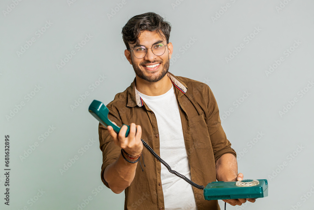 Hey you, call me back. Indian young man talking on wired landline vintage telephone of 80s, advertising proposition of conversation, online shopping, hotline. Arabian guy isolated on gray background Hey you, call me back. Indian young man talking on wired landline vintage telephone of 80s, advertising proposition of conversation, online shopping, hotline. Arabian guy isolated on gray background