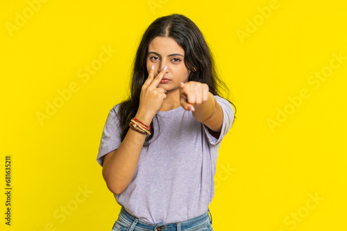 I am watching you. Confident attentive woman pointing at her eyes and camera, show I am watching you gesture spying on someone. Pretty disappointed Indian girl isolated on yellow studio background photo