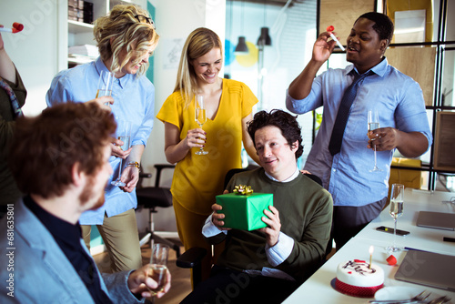 Businessman holding gift celebrating birthday with colleagues in office