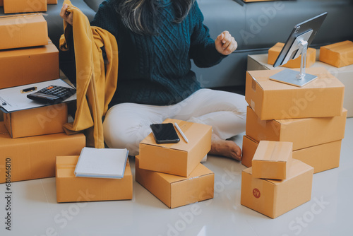 Startup SME small business entrepreneur of freelance Asian woman using a laptop with box Cheerful success Asian woman her hand lifts up online marketing packaging box and delivery SME idea concept