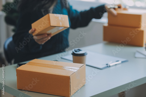 Startup SME small business entrepreneur of freelance Asian woman using a laptop with box Cheerful success Asian woman her hand lifts up online marketing packaging box and delivery SME idea concept © Sirikarn Rinruesee