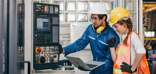 Male industrial engineer worker in hard helmet with female assistant using laptop control machine. Man and woman technician people working in heavy industry manufacturing factory.