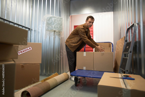 Mature man sorting boxes in storage unit he rents