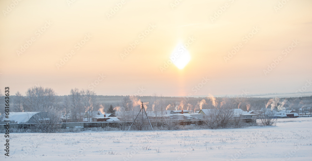 Frosty sunny day. Smoke comes out of the pipes above the village houses during heating. Rural winter landscape Frosty sunny day. Smoke comes out of the pipes above the village houses during heating. Rural winter landscape