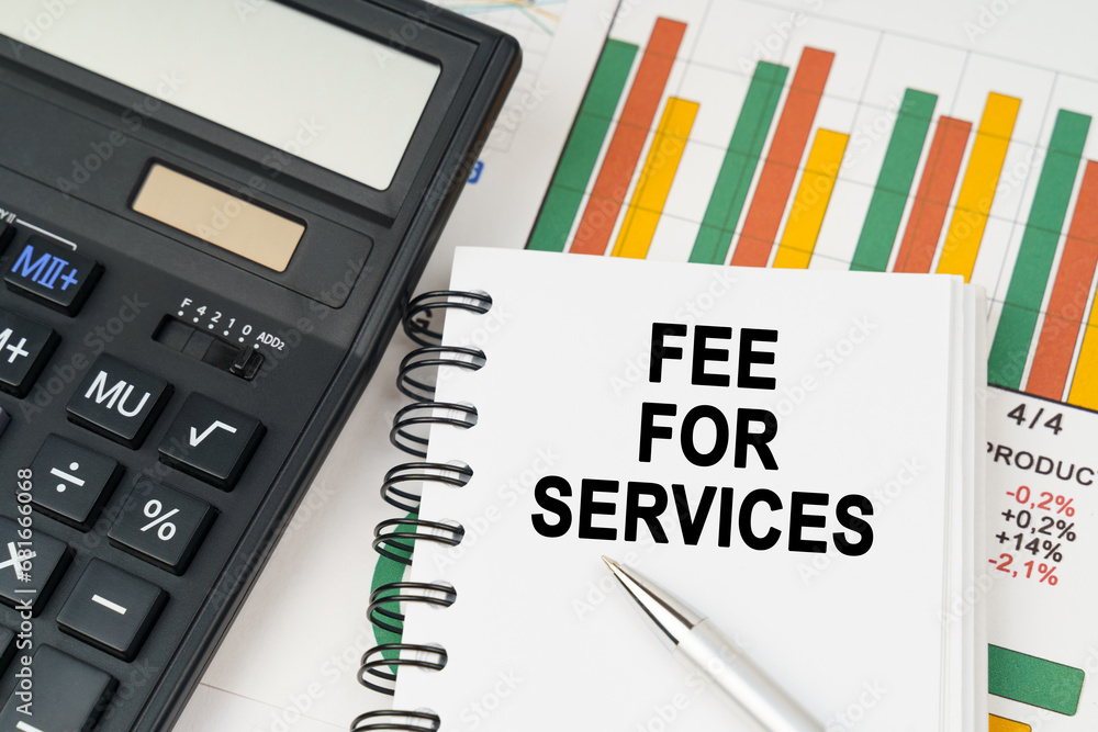 On business charts there is a calculator, a pen and a notepad with the inscription - fee for services On business charts there is a calculator, a pen and a notepad with the inscription - fee for services