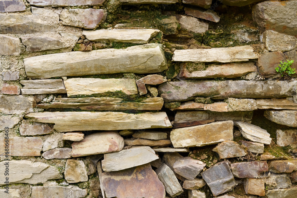 Old rough stone wall made of various square natural stones in beige, gray and brown colors. Old rough stone wall made of various square natural stones in beige, gray and brown colors.