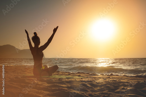 gorgeous woman practicing yoga, raising her arms, feeling so good and happy, young woman seeking enlightenment through meditation on the sea