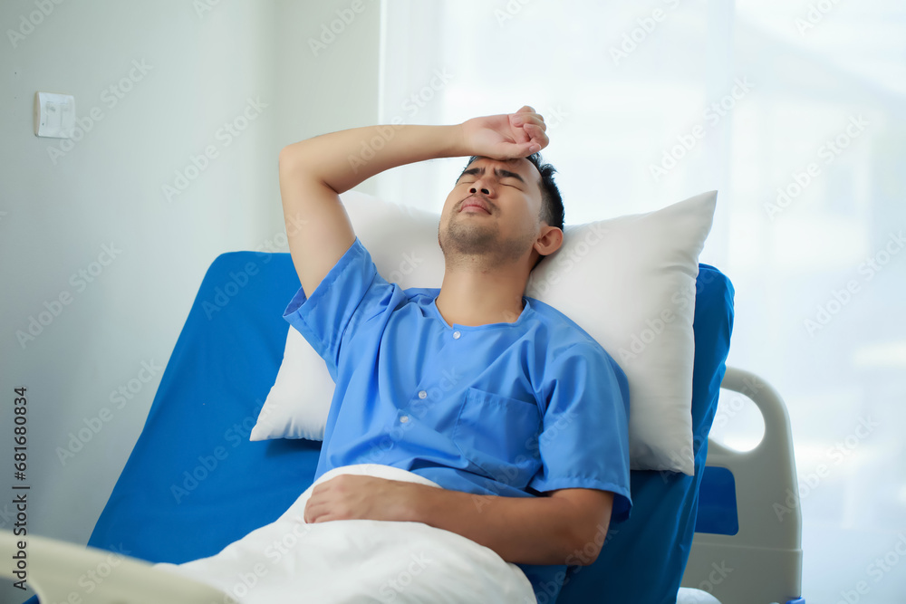 Obraz premium A patient is lying in a hospital bed in pain from an existing disease, The patient is feeling very stressed due to the disease he has while he is in the hospital.