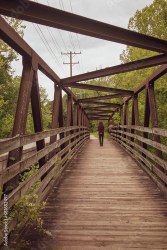 Walking into the future - a person walking away from the camera across a boardwalk footbridge in a nature area