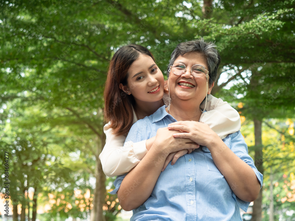 Happy smiling young daughter hugging with senior mother at park and looking camera. Mother day concept. family concept Happy smiling young daughter hugging with senior mother at park and looking camera. Mother day concept. family concept