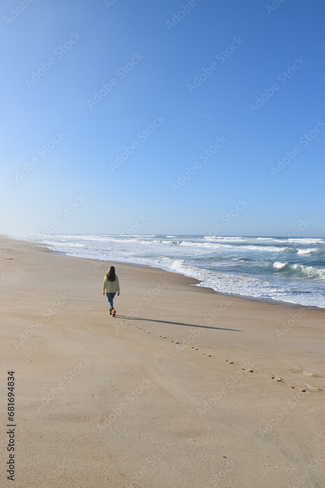 a girl walking on the beach in winter and leaving her footprints on the shore