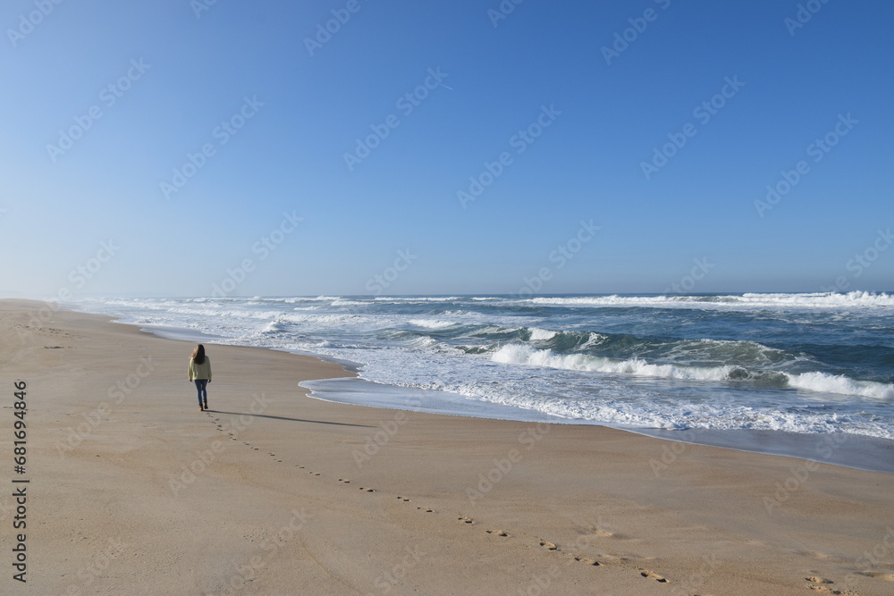 a girl walking on the beach in winter and leaving her footprints on the shore