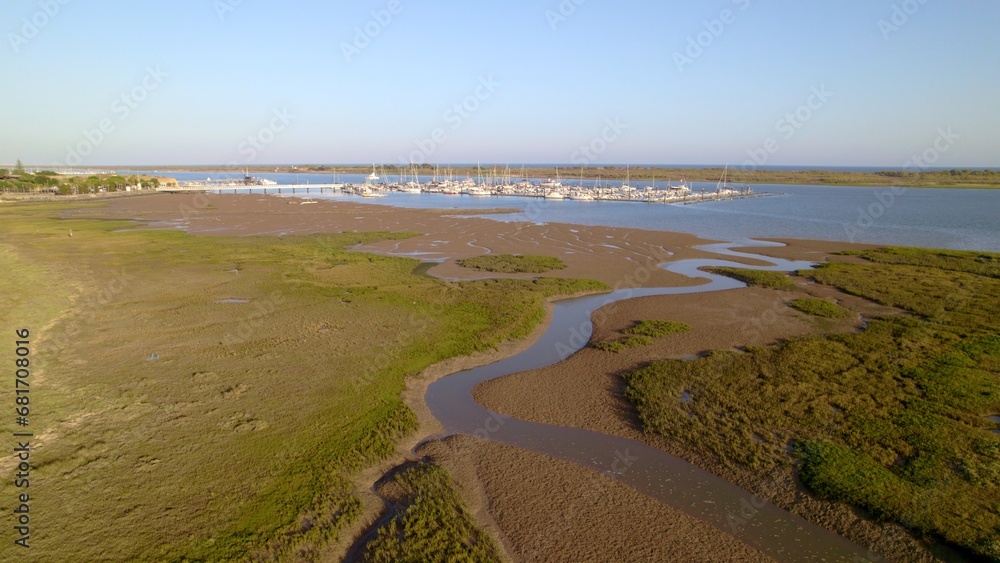 Sunset at the marina. Boats in the estuary with the sea in the background. Aerial view from drone with many boats of different types. El Rompido. Huelva. Andalusia. Spain. Sunset at the marina. Boats in the estuary with the sea in the background. Aerial view from drone with many boats of different types. El Rompido. Huelva. Andalusia. Spain.