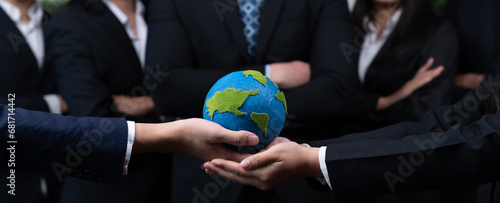 Top view business people holding Earth together in synergy as team building to utilize eco regulation for environmental protection by reducing CO2 emission to save Earth. Quaint photo