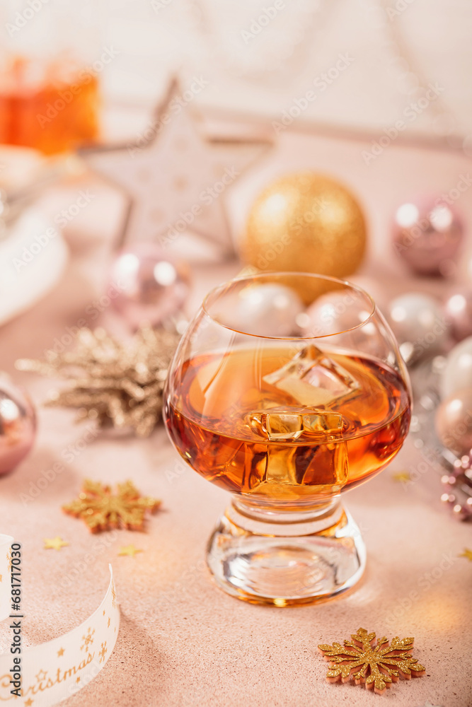 Glass of whiskey or bourbon with festive Christmas decoration on light beige background. New Year, Christmas and winter holidays whiskey mood concept Glass of whiskey or bourbon with festive Christmas decoration on light beige background. New Year, Christmas and winter holidays whiskey mood concept
