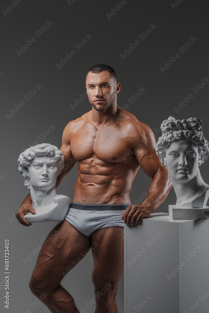 Fototapeta premium Rugged Beauty: Muscular Man and Ancient Greek Statues