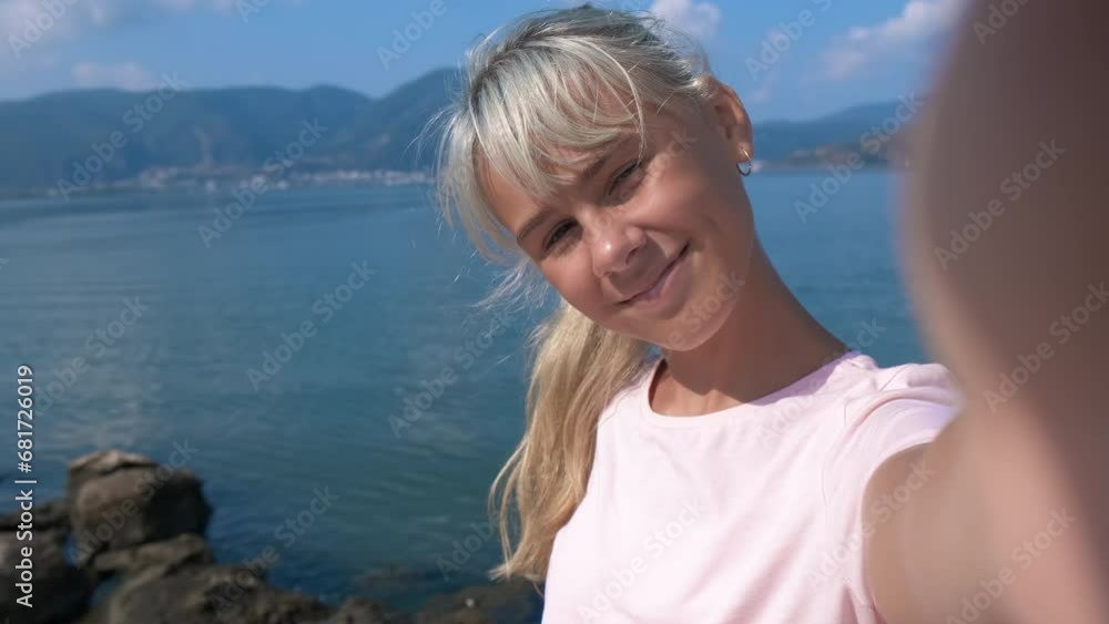 Happy teenager blogger by the sea. A young girl takes pictures of herself on a camera against the backdrop of a seascape. Happy teenager blogger by the sea. A young girl takes pictures of herself on a camera against the backdrop of a seascape.