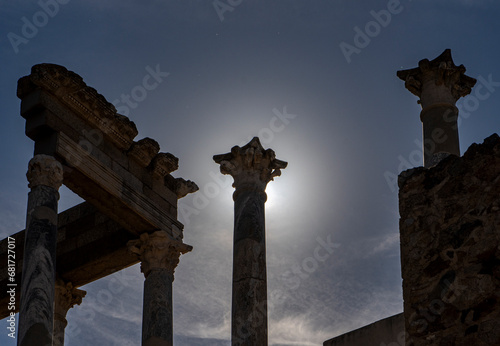 Backlit silhouette with the capital of a column blocking the light of the moon as if it were a lunar eclipse from the ruins of the Roman theater in Mérida, creating a divine glow or shine. photo