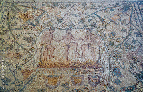 Archaeological remains of Roman mosaic floor of men holding hands crushing grapes to make wine, with branches of grapes and birds as decoration. Merida archaeological complex of Casa Mithraeum