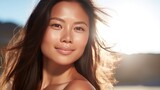Celebrate radiant skin! An Asian woman with a sunburned face embraces the summer sun outdoors. Convey the importance of sun protection and skincare with this vibrant stock image.