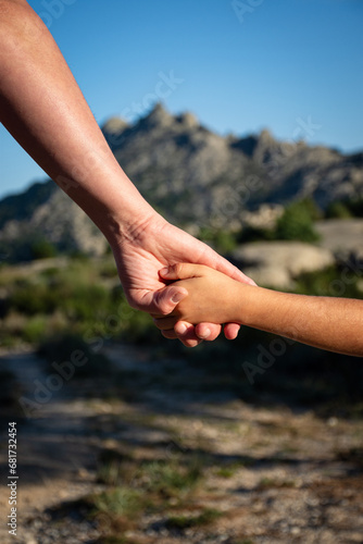una madre sosteniendo la mano de su hijo, con una montaña al fondo © MCarmen