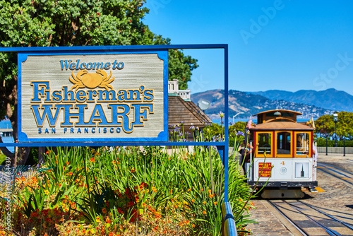 Welcome sign for Fisherman’s Wharf, San Francisco and trolley with tourists and mountain #681734439
