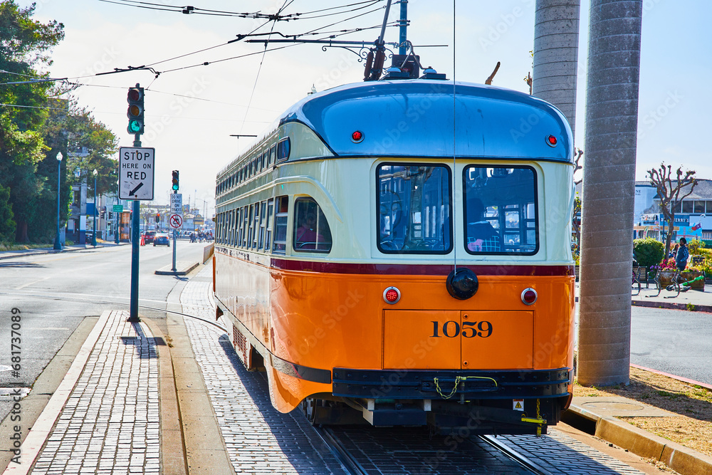 Striped blue, white, and orange streetcar number 1059 with wires overhead in San Francisco, CA