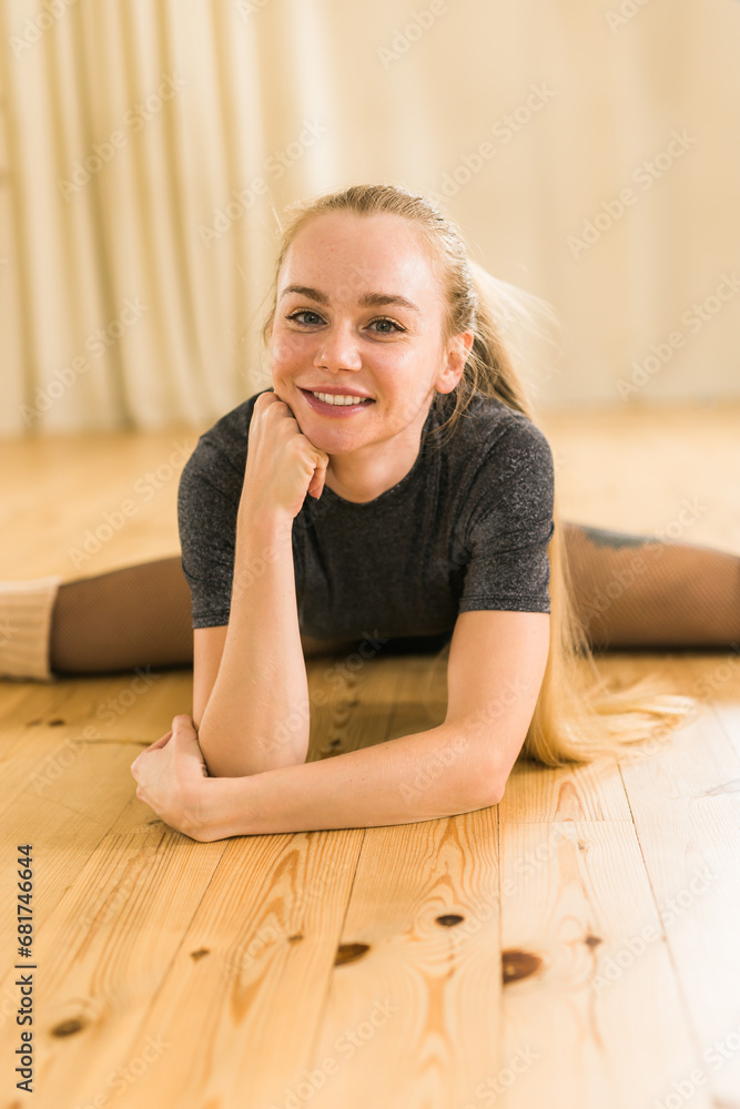 Young slim woman is doing some twine to stretch. Joyful talented woman in fitness class. Female ballerina portrait Young slim woman is doing some twine to stretch. Joyful talented woman in fitness class. Female ballerina portrait