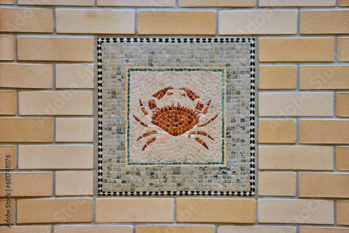 Colorful crab mosaic art tiles with abstract animal crustacean image on yellow brick wall