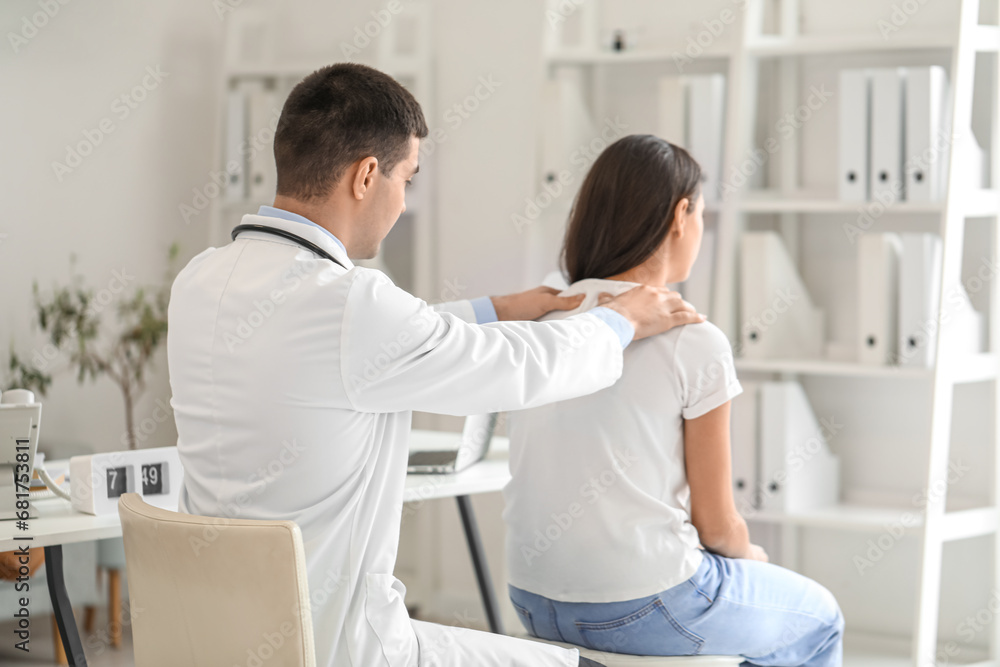 Male doctor checking posture of young woman in clinic - obrazy, fototapety, plakaty 
