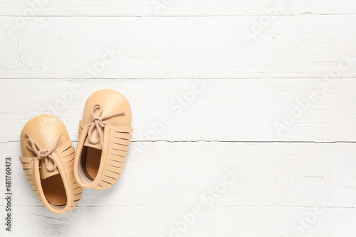 Stylish baby shoes on white wooden background