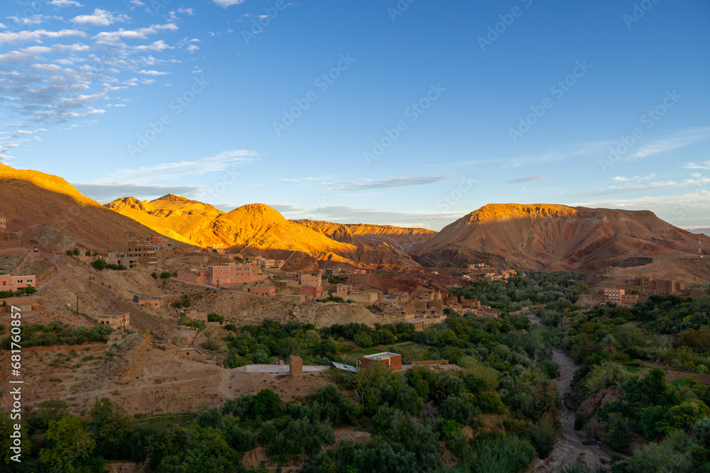 Photo of the Dades Gorge in Morocco. Photo at sunset with blue sky. Terracotta-colored buildings typical of the area.