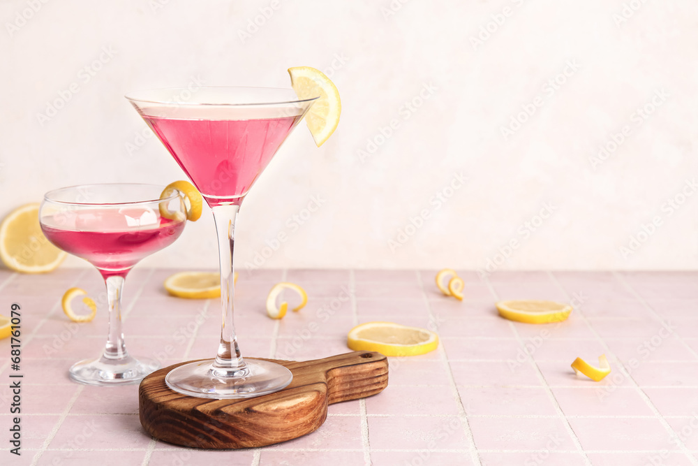 Glasses of Cosmopolitan cocktail with lemon on pink tile table Glasses of Cosmopolitan cocktail with lemon on pink tile table
