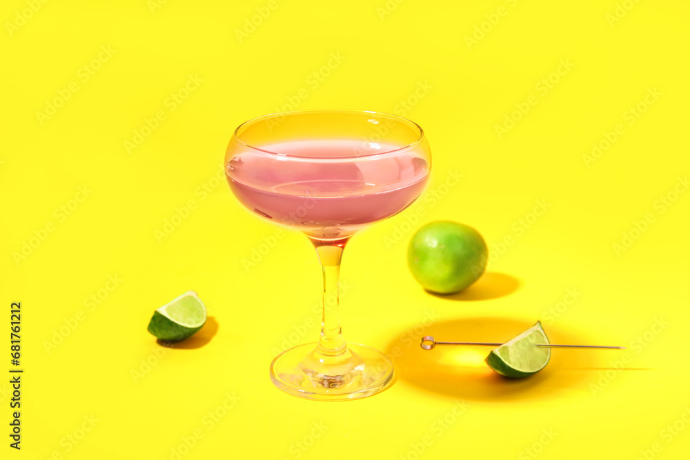 Glass of Cosmopolitan cocktail with lime on yellow background Glass of Cosmopolitan cocktail with lime on yellow background
