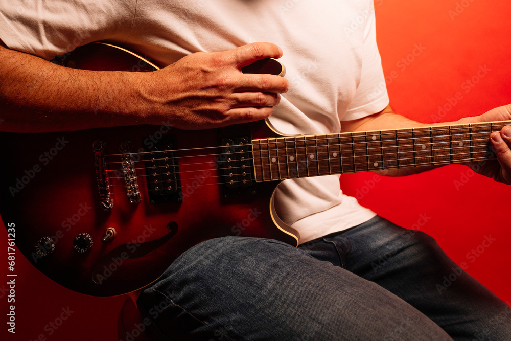 Fototapeta premium Man playing electric guitar on red background